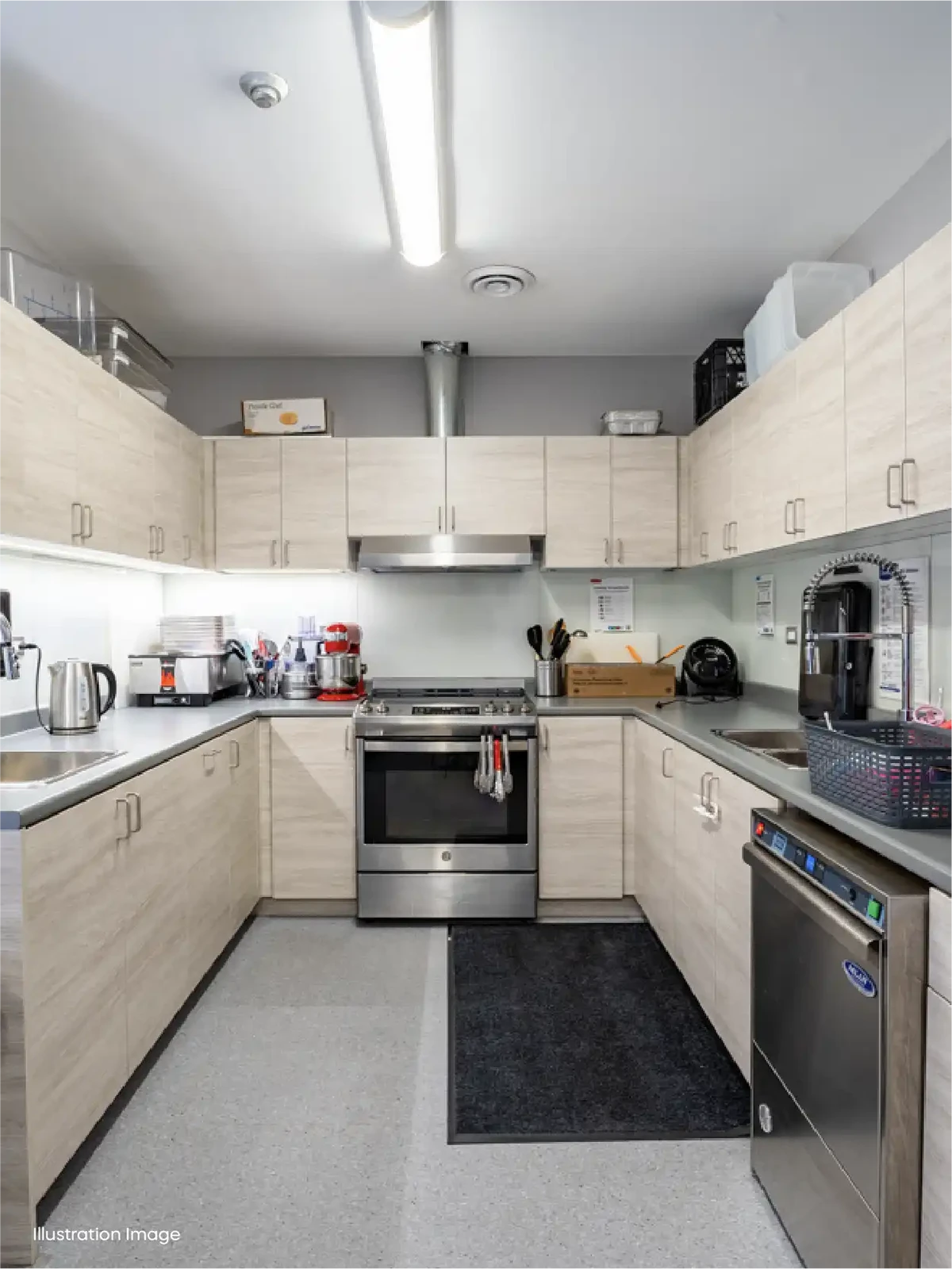 Modern office kitchen with light wood cabinets, stainless steel appliances, and organized utensils—similar in cleanliness and organization to top early learning centres or preschool schools near me. Overhead lighting brightens the welcoming space.